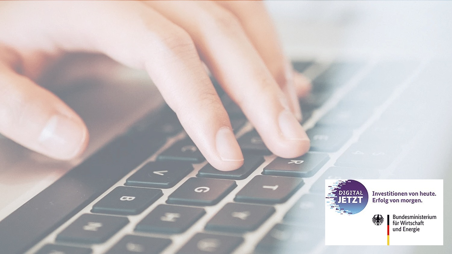 Eine Nahaufnahme der Hand einer Person, die auf einer Laptoptastatur tippt. In der unteren linken Ecke sind Logos und Texte von „Digital Jetzt“ und „Bundesministerium für Wirtschaft und Energie“ mit dem Slogan „Investitionen von heute. Erfolg von morgen“ zu sehen.