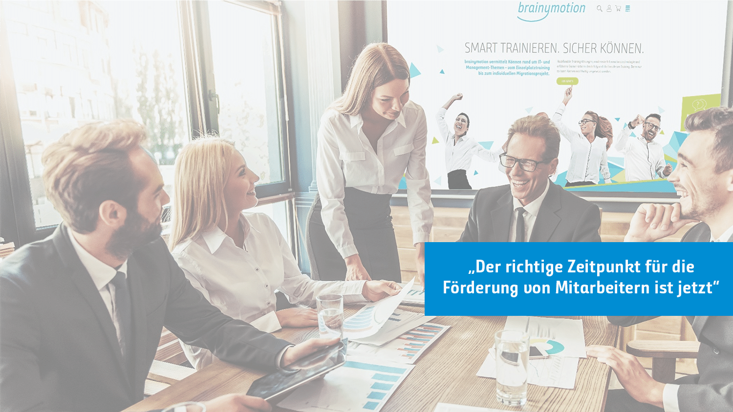 Eine Gruppe von Geschäftsleuten sitzt an einem Konferenztisch und führt eine lebhafte Diskussion. Auf einem Bildschirm im Hintergrund werden der Text „brainymotion“ und Präsentationsfolien angezeigt. Ein blaues Banner überlagert das Bild mit dem Text: „Der richtige Zeitpunkt für die Förderung von Mitarbeitern ist jetzt.“